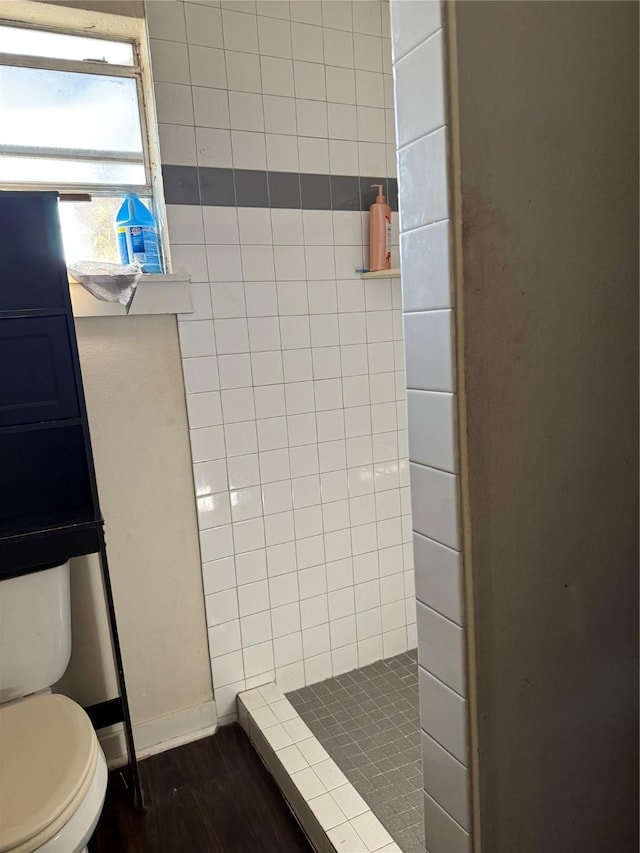 bathroom with tiled shower, wood-type flooring, and toilet