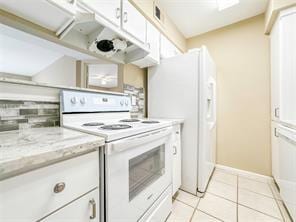 kitchen featuring light tile patterned floors, light stone countertops, white cabinets, and white range with electric stovetop