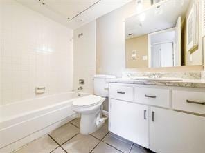 full bathroom featuring tile patterned flooring, vanity, tiled shower / bath combo, and toilet