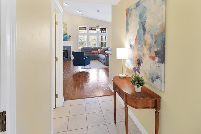 hallway with light tile patterned flooring and vaulted ceiling