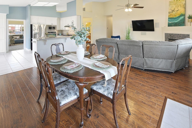 dining area featuring dark wood-type flooring, ceiling fan, and a towering ceiling