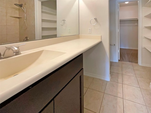 bathroom with tile patterned flooring, vanity, and a tile shower