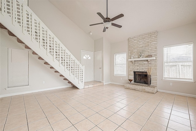 unfurnished living room with light tile patterned flooring, a brick fireplace, and a wealth of natural light