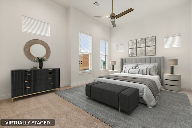 bedroom with ceiling fan, light carpet, and a high ceiling