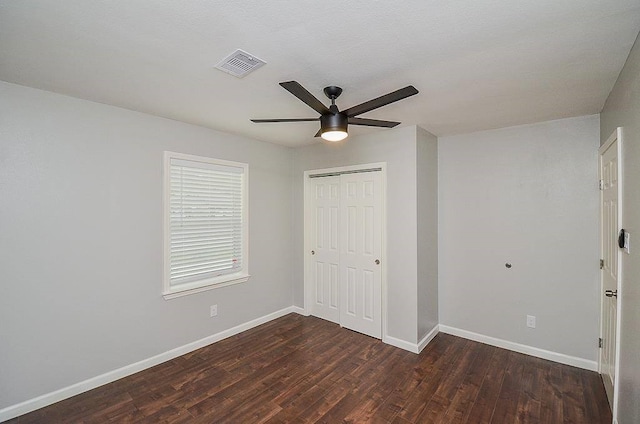 unfurnished bedroom featuring baseboards, visible vents, dark wood finished floors, ceiling fan, and a closet