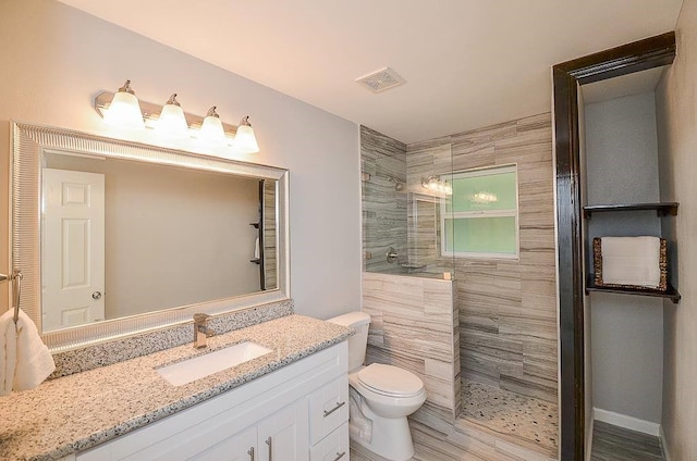 bathroom featuring visible vents, vanity, toilet, and a walk in shower