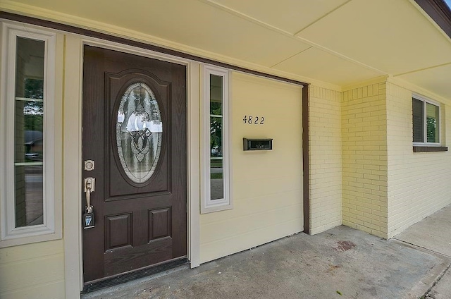 entrance to property with covered porch and brick siding