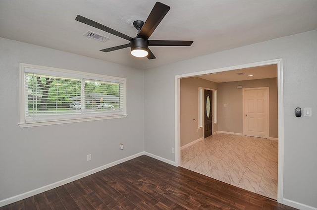 empty room featuring baseboards, visible vents, ceiling fan, and wood finished floors