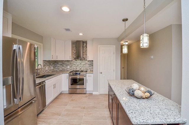 kitchen with a sink, white cabinets, appliances with stainless steel finishes, backsplash, and wall chimney exhaust hood