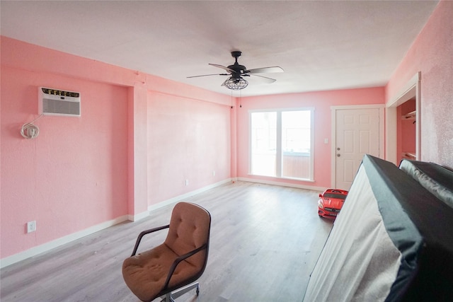 living area featuring ceiling fan, a wall mounted air conditioner, and light hardwood / wood-style floors