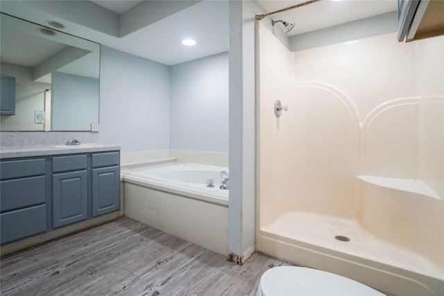 full bathroom with wood-type flooring, separate shower and tub, vanity, and toilet