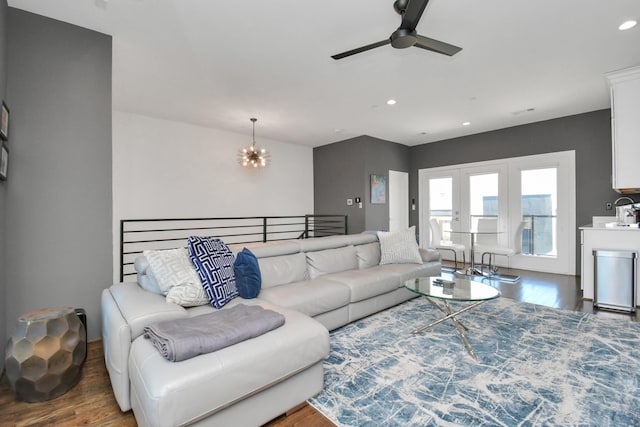 living room featuring ceiling fan with notable chandelier, dark wood-type flooring, and french doors