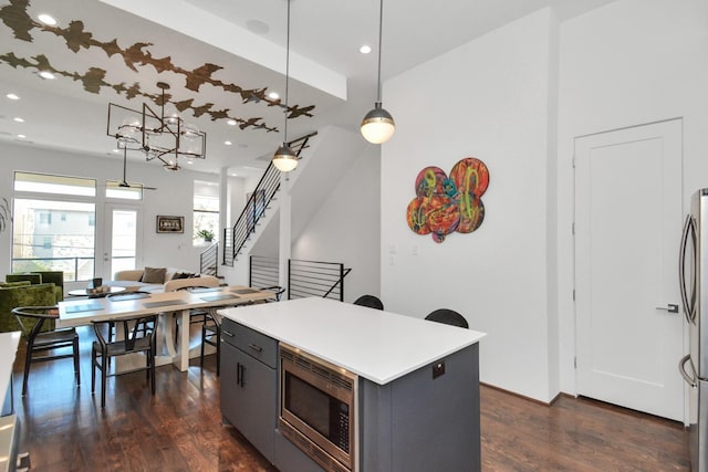 kitchen featuring gray cabinetry, dark hardwood / wood-style flooring, hanging light fixtures, a center island, and stainless steel appliances