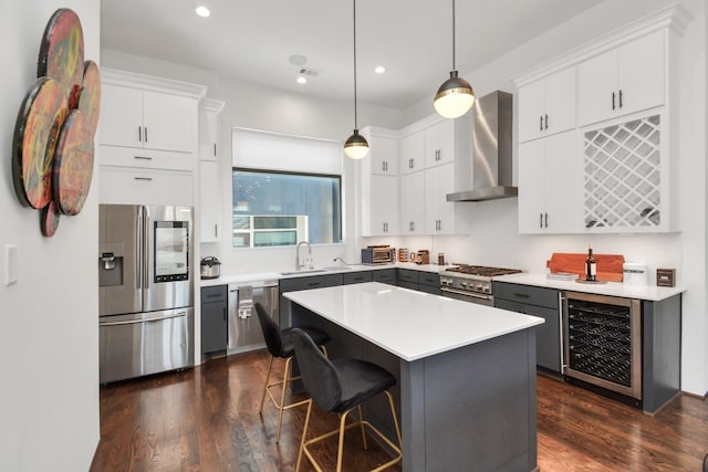 kitchen featuring wall chimney exhaust hood, white cabinetry, appliances with stainless steel finishes, a kitchen island, and pendant lighting