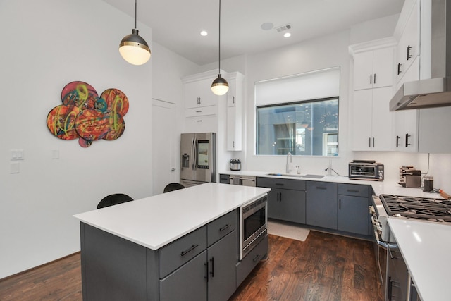 kitchen with sink, appliances with stainless steel finishes, hanging light fixtures, a center island, and white cabinets