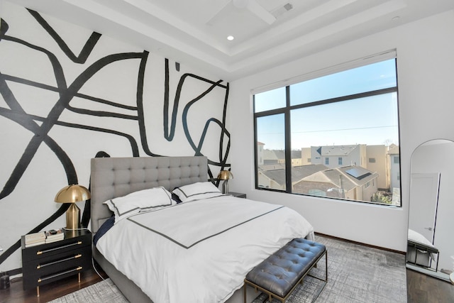 bedroom with dark wood-type flooring and a tray ceiling