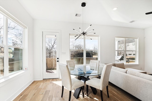 dining area with a notable chandelier, light hardwood / wood-style floors, and a wealth of natural light