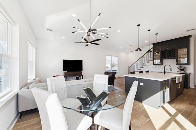 dining area with an inviting chandelier, wet bar, and light wood-type flooring