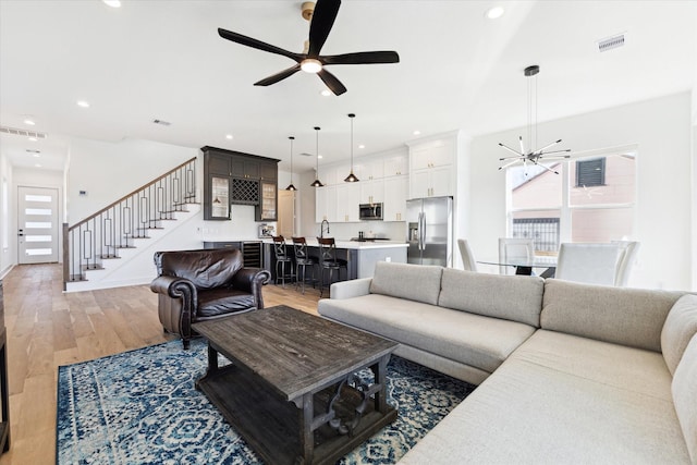 living room with hardwood / wood-style flooring and ceiling fan with notable chandelier