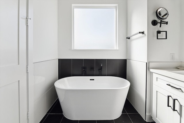 bathroom with vanity, tile patterned flooring, a bathtub, and tile walls