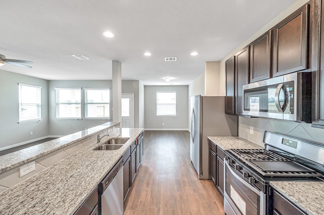 kitchen with sink, light hardwood / wood-style flooring, dark brown cabinets, stainless steel appliances, and light stone counters