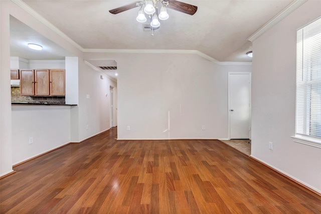 unfurnished living room with hardwood / wood-style flooring, ornamental molding, and ceiling fan