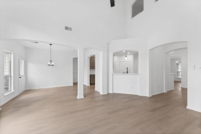 unfurnished living room featuring hardwood / wood-style flooring, a high ceiling, and a notable chandelier