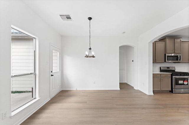 kitchen featuring pendant lighting, appliances with stainless steel finishes, light hardwood / wood-style flooring, and a notable chandelier