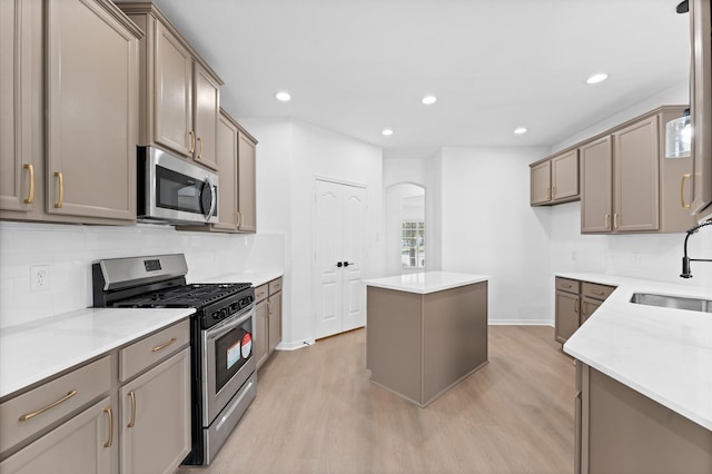 kitchen with stainless steel appliances, a kitchen island, sink, and light hardwood / wood-style flooring