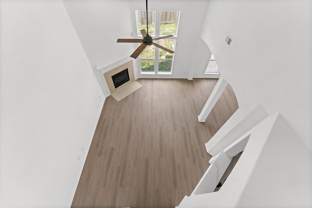 unfurnished living room featuring a tiled fireplace, wood-type flooring, and ceiling fan