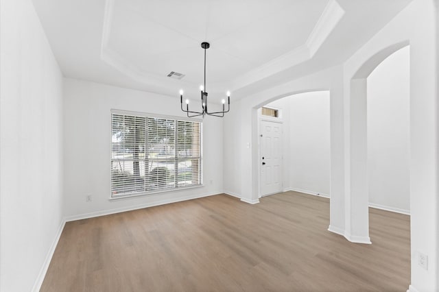 unfurnished dining area featuring an inviting chandelier, crown molding, light hardwood / wood-style flooring, and a raised ceiling