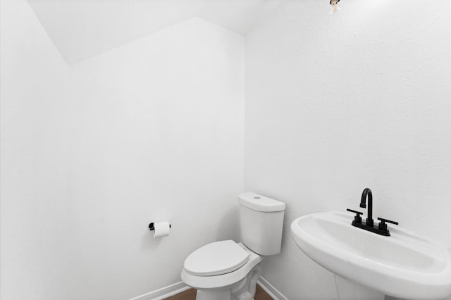 bathroom featuring hardwood / wood-style flooring, lofted ceiling, sink, and toilet