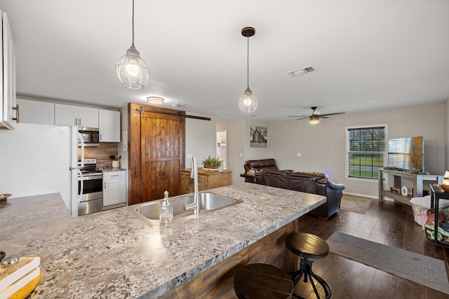 kitchen with sink, hanging light fixtures, stainless steel appliances, and a barn door