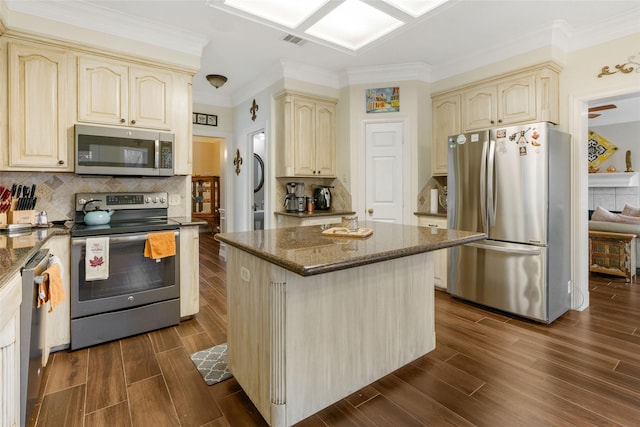 125 Indian Warrior Trl, Lake Jackson, TX 77566 - kitchen featuring crown molding, appliances with stainless steel finishes, dark stone countertops, backsplash, and a kitchen island