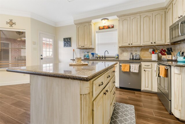 125 Indian Warrior Trl, Lake Jackson, TX 77566 - kitchen featuring appliances with stainless steel finishes, ornamental molding, a kitchen island, decorative backsplash, and dark stone counters