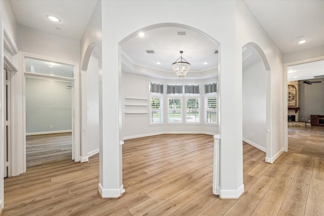 interior space with a large fireplace, ceiling fan with notable chandelier, and light hardwood / wood-style flooring