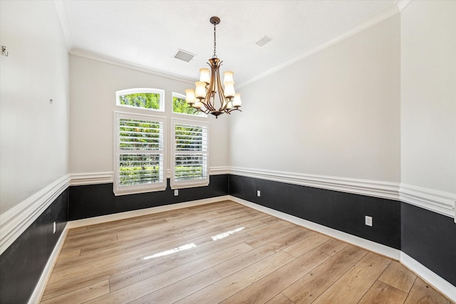 spare room with an inviting chandelier, light hardwood / wood-style flooring, and ornamental molding