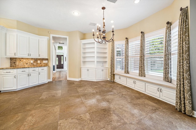 kitchen with light stone countertops, a healthy amount of sunlight, white cabinets, and decorative backsplash