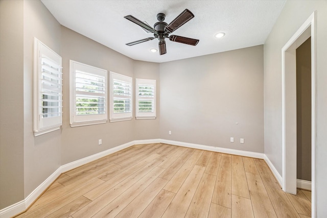 spare room with a textured ceiling, ceiling fan, and light hardwood / wood-style flooring