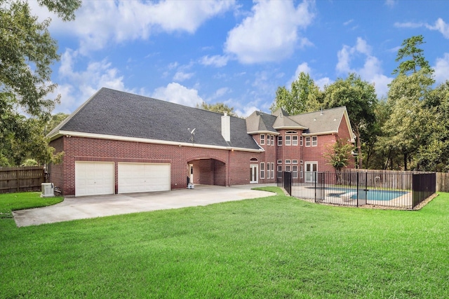 rear view of house with a yard, a fenced in pool, a patio area, and a garage