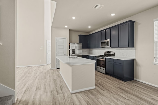 kitchen with sink, light hardwood / wood-style flooring, an island with sink, and appliances with stainless steel finishes