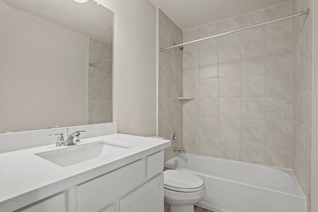 full bathroom featuring tiled shower / bath, vanity, and toilet