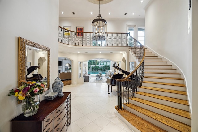 foyer entrance featuring crown molding, plenty of natural light, a chandelier, and a high ceiling