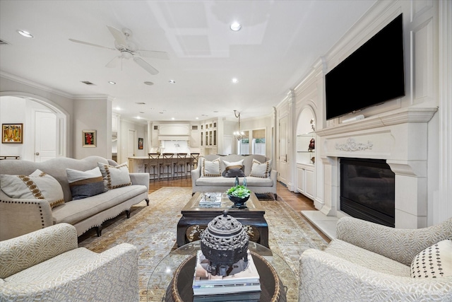 living room with hardwood / wood-style flooring, ceiling fan with notable chandelier, and ornamental molding