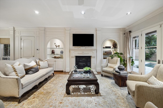 living room featuring built in shelves, wood-type flooring, and ornamental molding