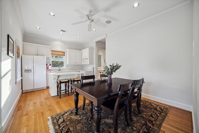 dining room with ornamental molding, sink, ceiling fan, and light wood-type flooring