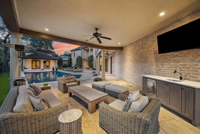 view of patio / terrace featuring sink, ceiling fan, an outdoor structure, an outdoor hangout area, and beverage cooler