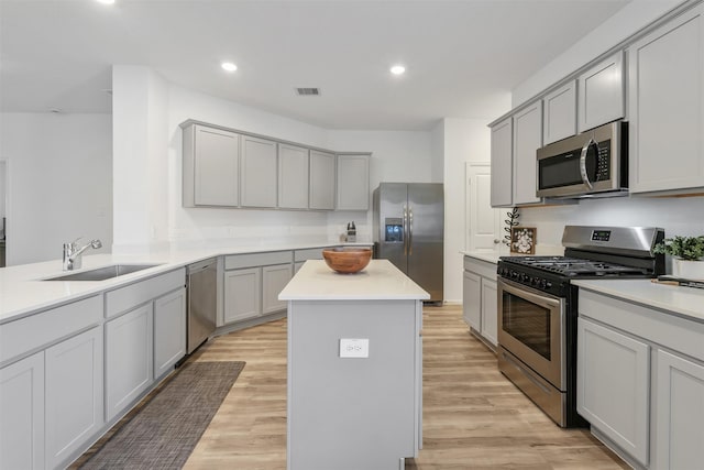 kitchen with sink, gray cabinets, stainless steel appliances, and a center island