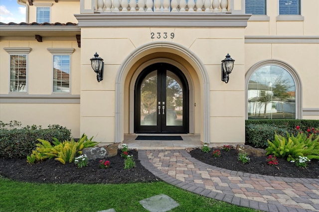 entrance to property featuring french doors, a tile roof, and stucco siding