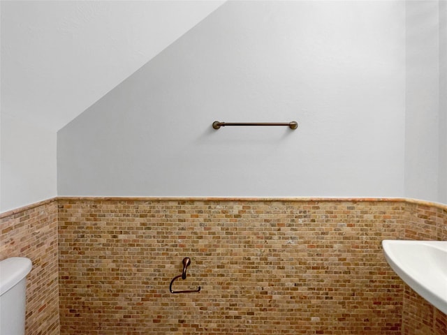 bathroom featuring lofted ceiling, sink, and toilet